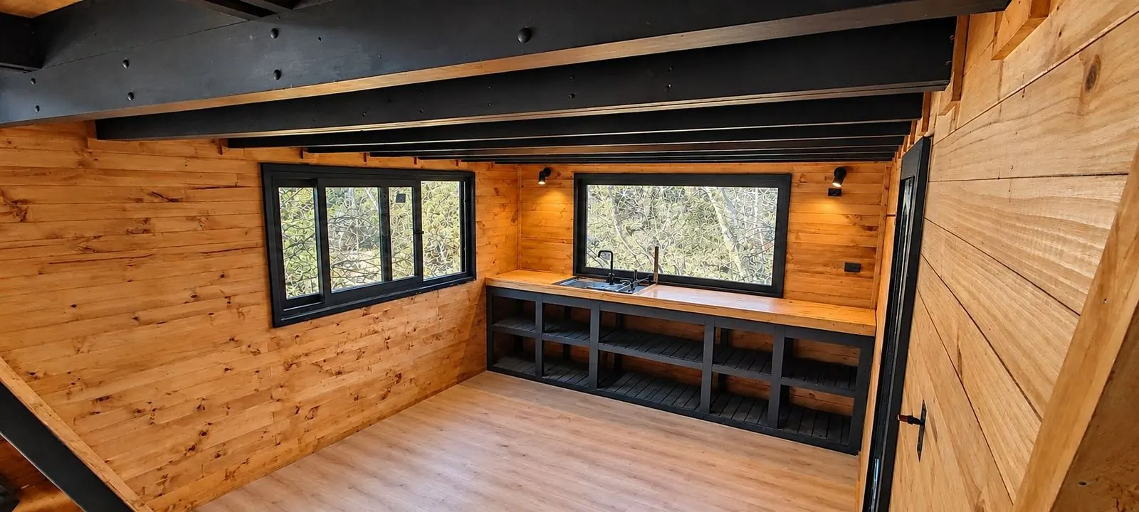 Cocina integrada de madera con mueble negro a medida y ventanal